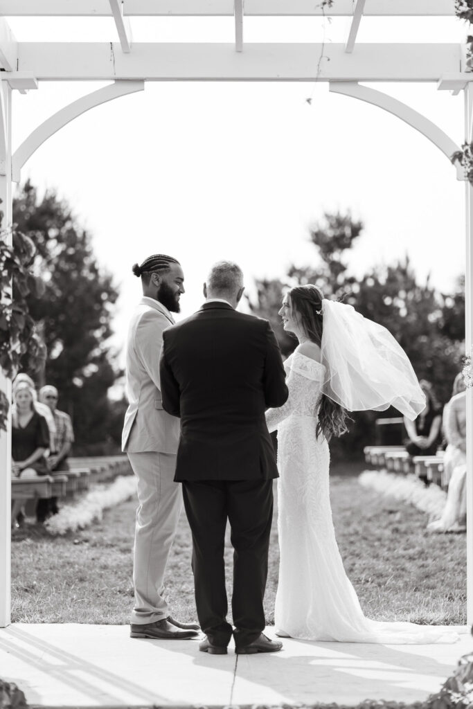 bride, groom, and officiant standing at wedding ceremony