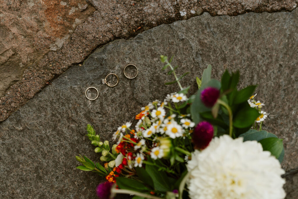 adventurous elopement flat lay with rings and wildflower bouquet