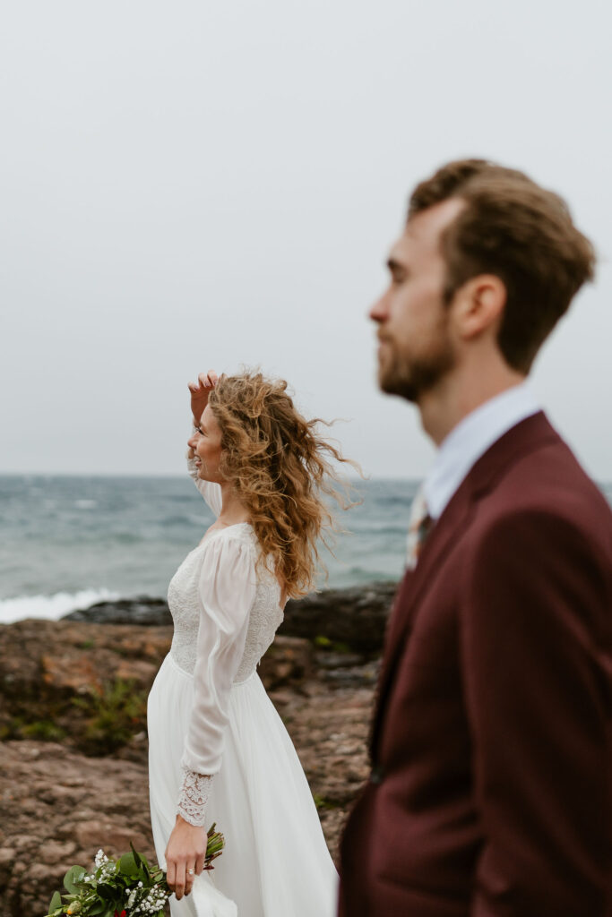 Annie and Josiah pause during their hike to take photos with Gitchi Gummi (Lake Superior) in the background, creating lasting memories of their north shore elopement.