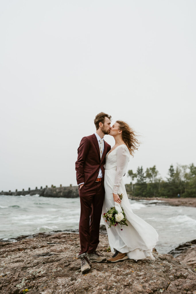 Annie and Josiah pause during their hike to take photos with Gitchi Gummi (Lake Superior) in the background, creating lasting memories of their north shore elopement.