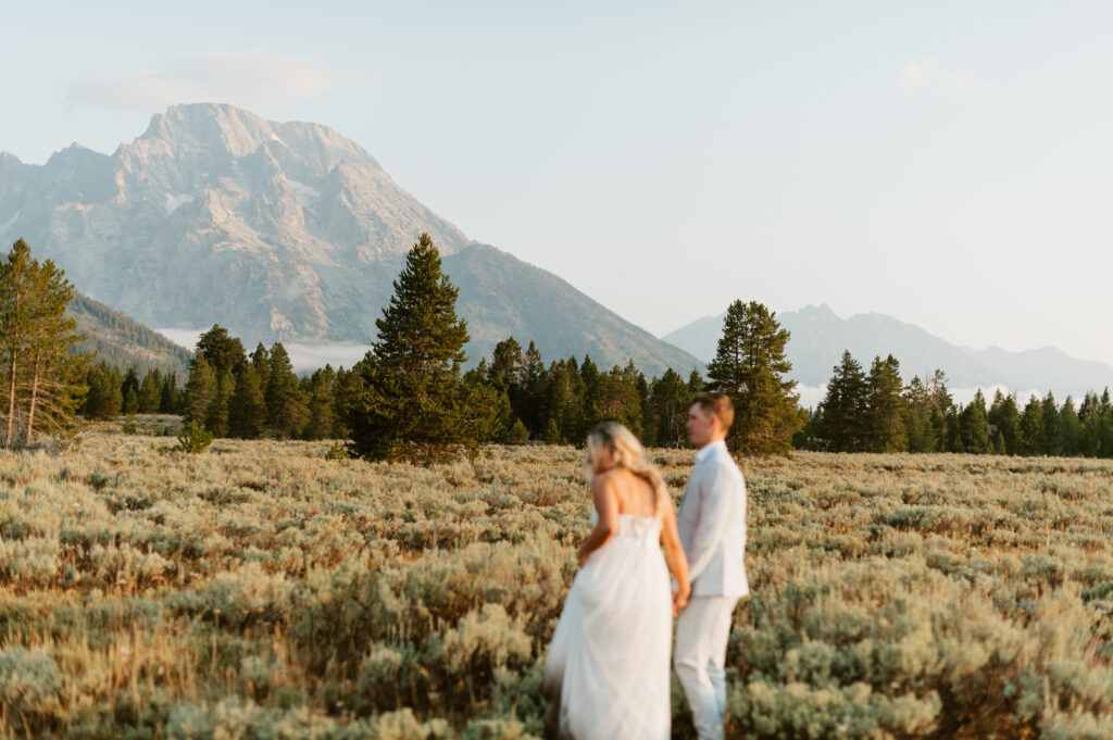 Cam and Ashley hold hands at sunrise in Grand Teton National Park