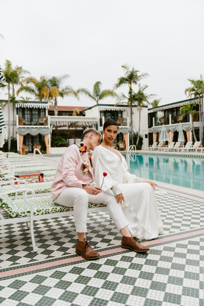Two brides sit on a pool chair at The Lafayette Hotel pool for their San Diego Elopement