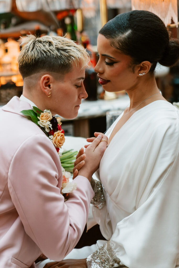 A close-up of the two brides facing each other holding hands against the backdrop of The Lafayette Hotel's mid-century modern architecture in San Diego.
