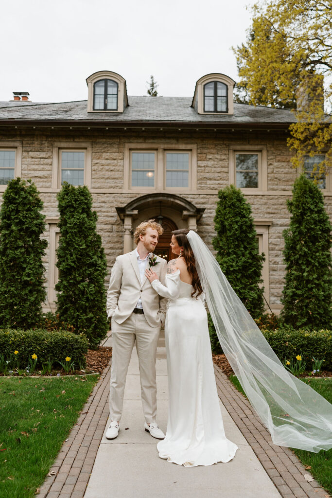 Bride and groom stand in front of St. Paul College Clubs vintage mansion