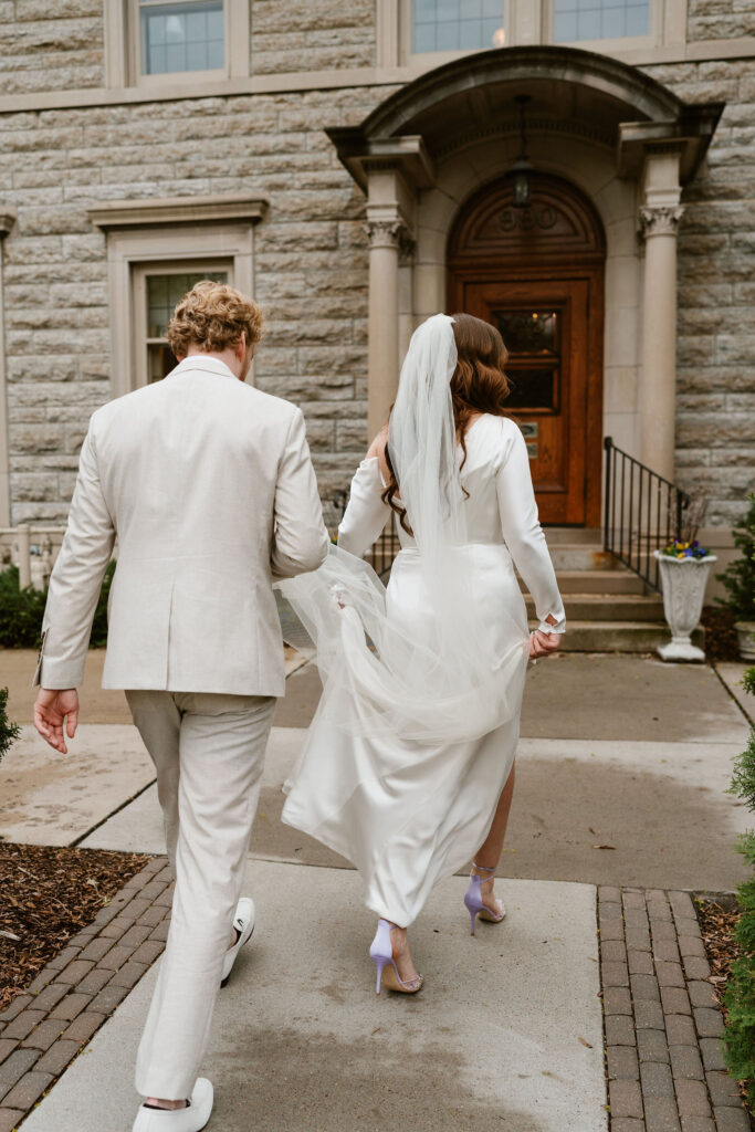 Bride and groom stand in front of St. Paul College Clubs vintage mansion