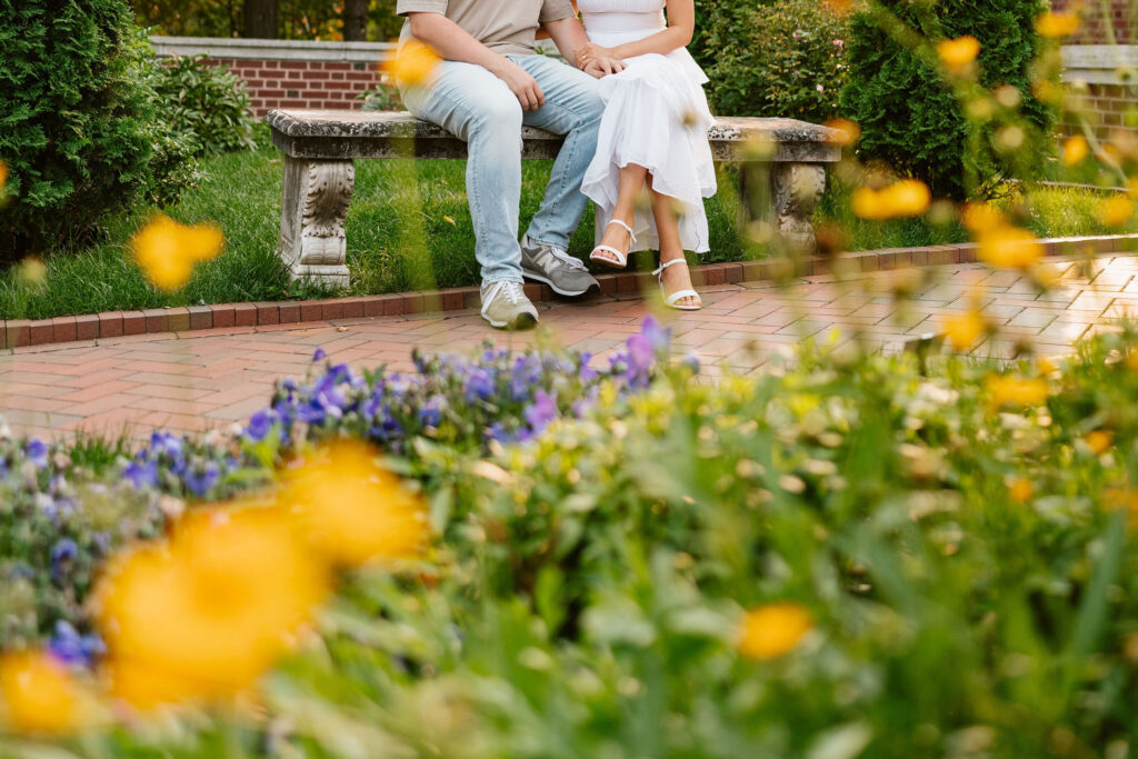 A couple sits in the gardens at Glensheen Mansion for some classy engagement photos