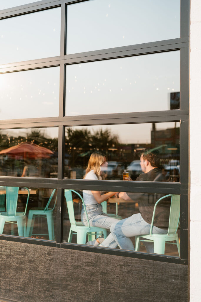 Couple sits in Wild State Cider to share some drinks during their engagement session