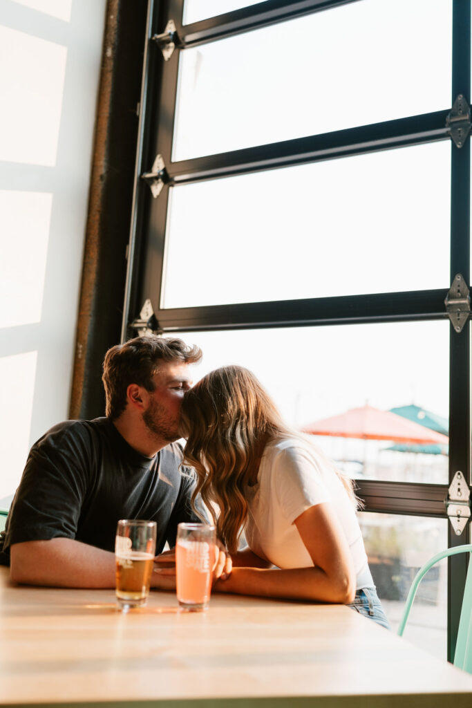 Couple sits in Wild State Cider to share some drinks during their engagement session