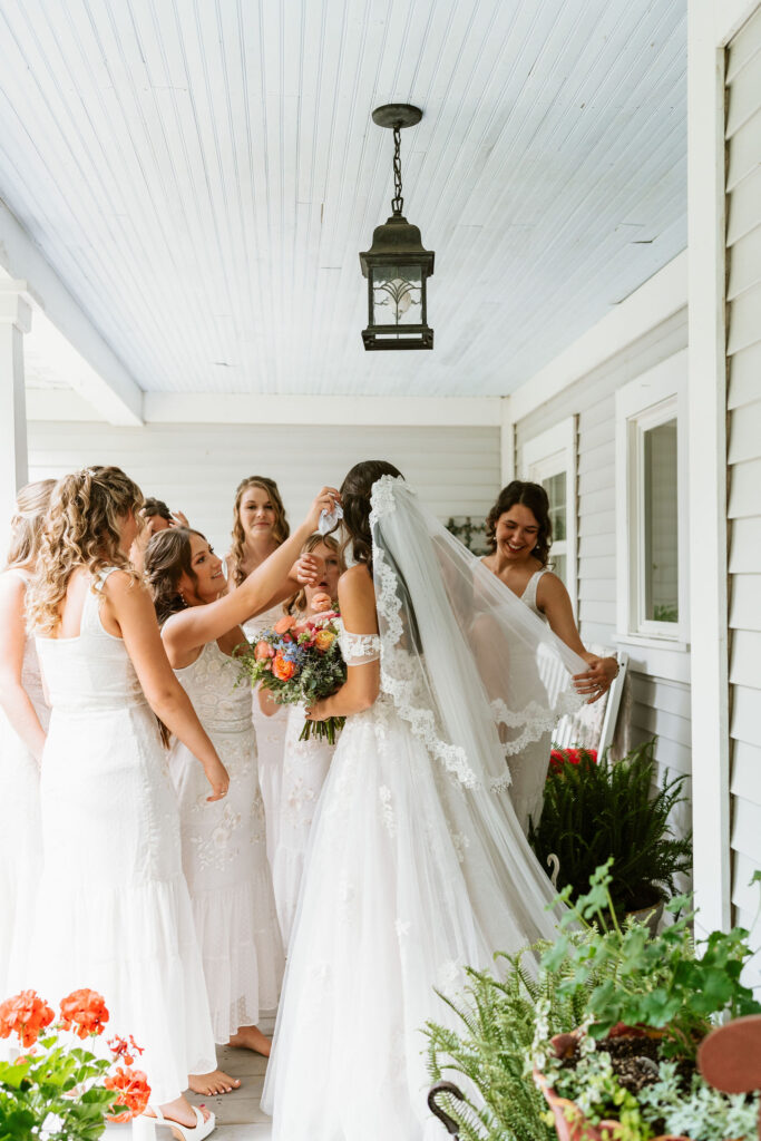 A bride stands with her bridesmaids on a front porch of a Wisconsin home before her wedding ceremony