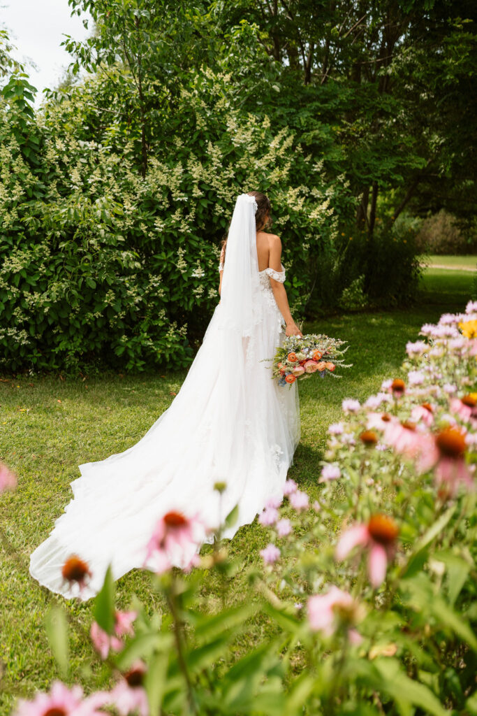 A bride walks through a stunning backyard with colorful florals