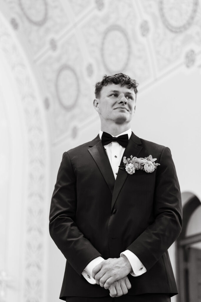 Groom watches as his bride walks down the aisle at their Wisconsin wedding ceremony