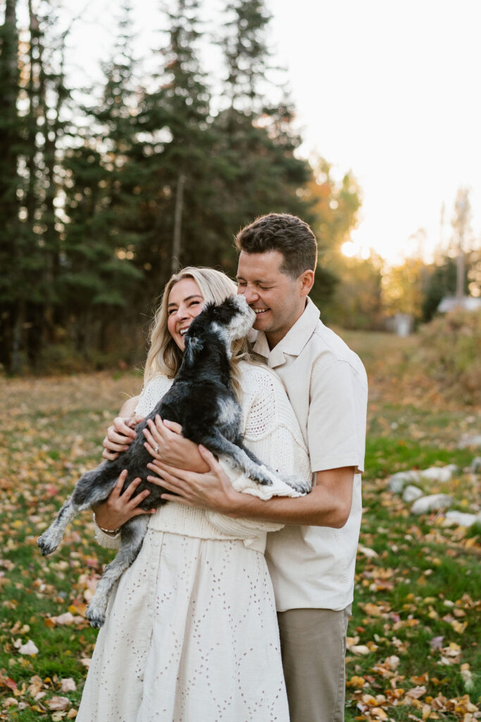 Couple takes engagement photos with their dog in the fall foliage at their family's Minnesota cabin on the lake