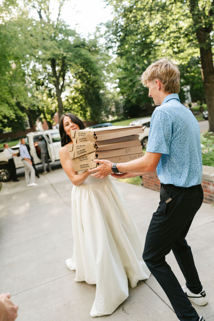 Bride grabs a stack of pizzas for their reception dinner
