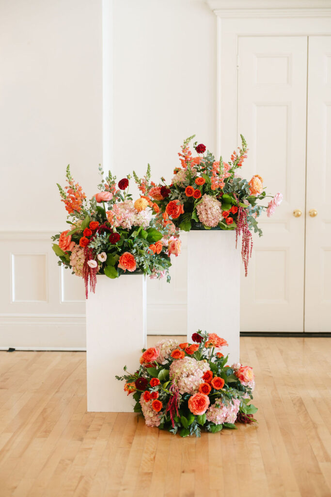 Colorful floral installations on white podiums