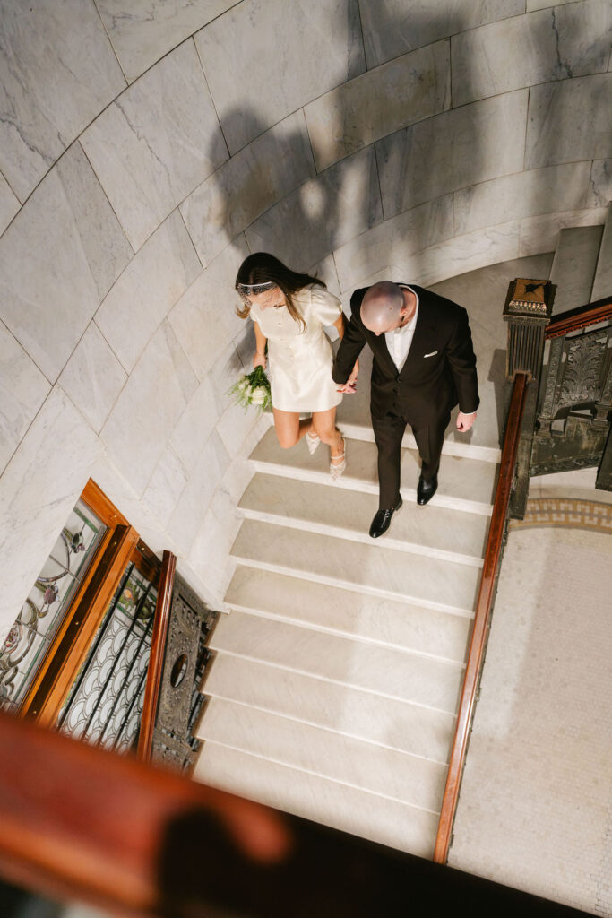 Bride and groom walk down a staircase in Minneapolis City Hall