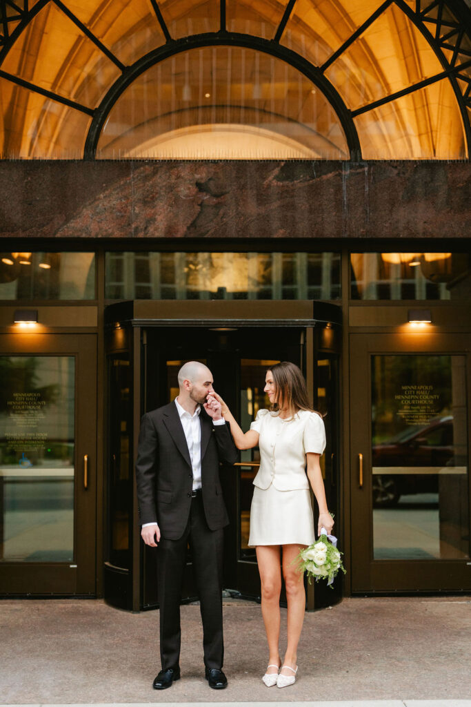 Groom kisses bride's hand outside of Minneapolis City Hall