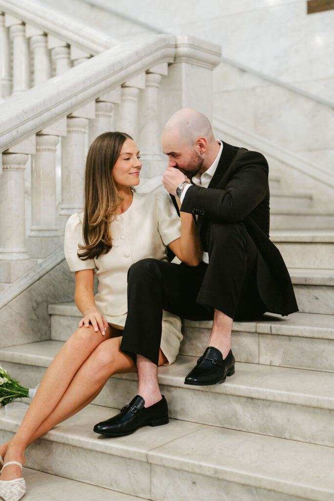 Bride and groom sit on a staircase in Minneapolis City Hall