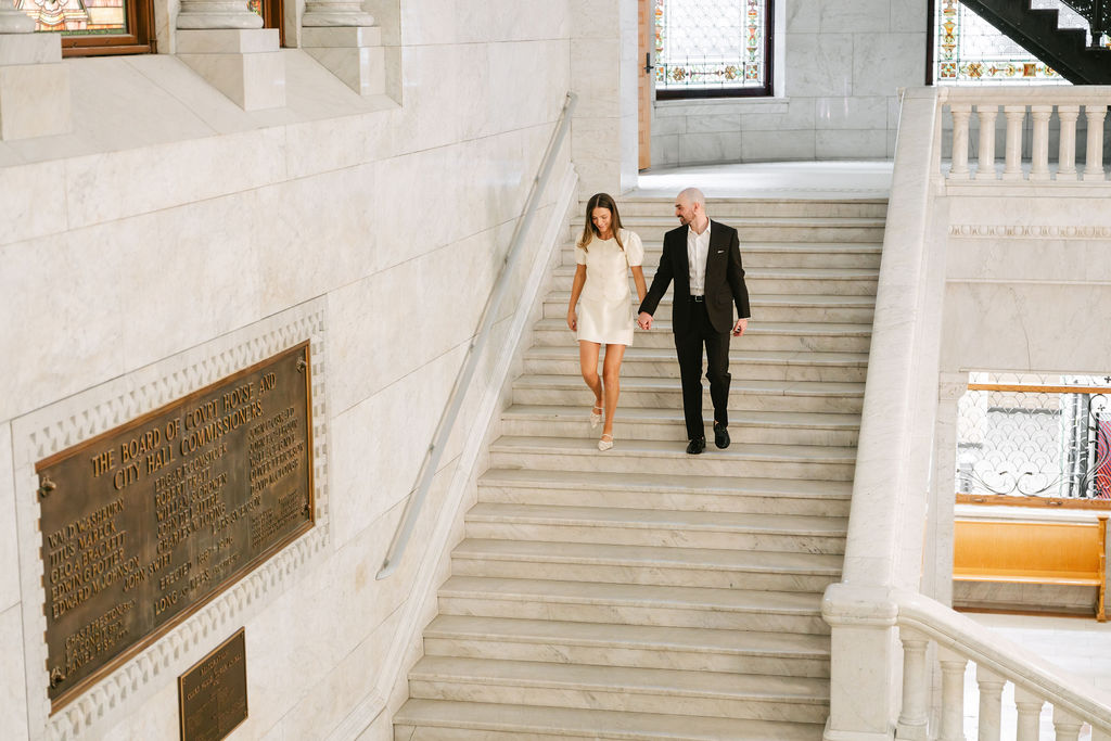 Bride and groom walk down a staircase in Minneapolis City Hall