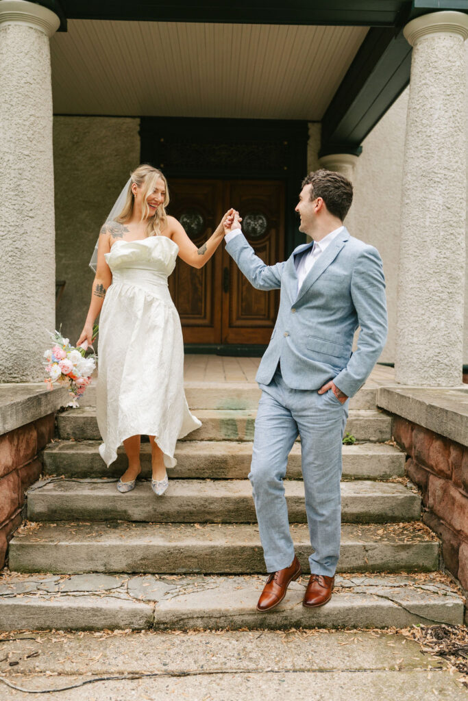 Bride and groom walk down the front steps of a private estate in St. Paul